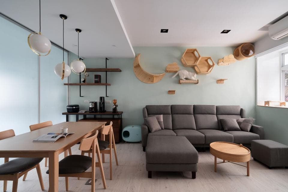 這張「客廳」的照片是一個簡約時尚的現代居家空間,佈置著舒適的沙發和木質餐桌,牆上則裝飾著貓咪專屬的玩樂空間,營造出溫馨舒適的氛圍。