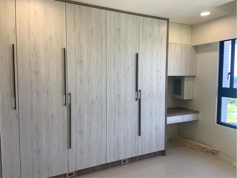 這張照片是一間房間裡面的衣櫃,衣櫃有六扇門,每扇門都有黑色的把手。衣櫃是木質的,表面紋理像是木頭,顏色是淺色的。