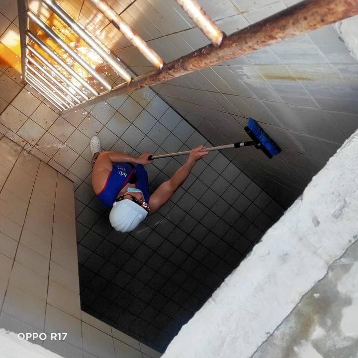 這張照片是一個正在用刷子清潔浴室地板的女性。