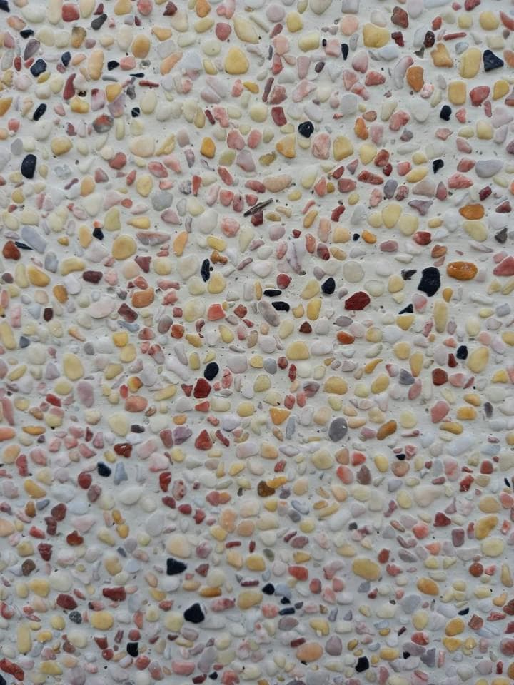 1) 照片顯示一塊由各種尺寸和顏色的石頭組成的混凝土表面