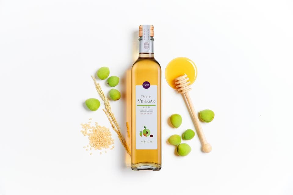 這張「梅子醋」的照片是,有一瓶梅子醋、蜂蜜、梅子、米和木棍。