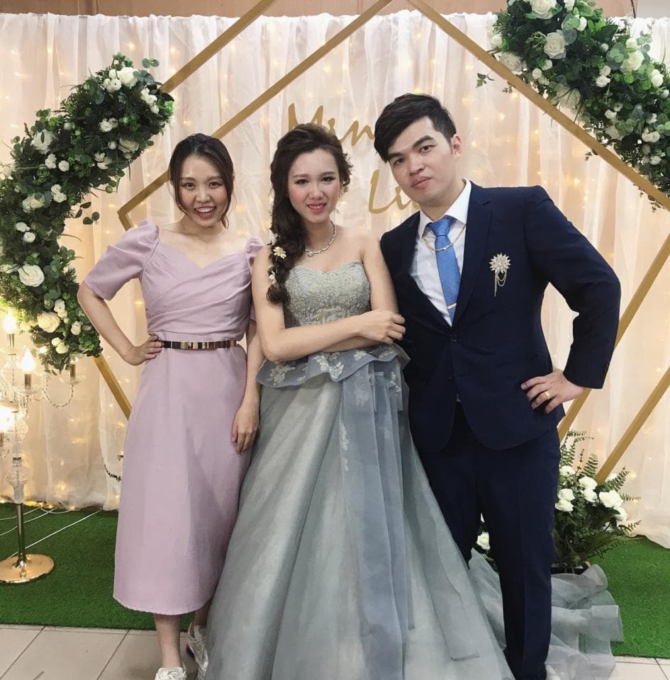 這張「婚禮」的照片是一個穿著淺紫色禮服的女生站在中間,另外兩個女生穿著白色禮服和藍色西裝站在她兩邊。