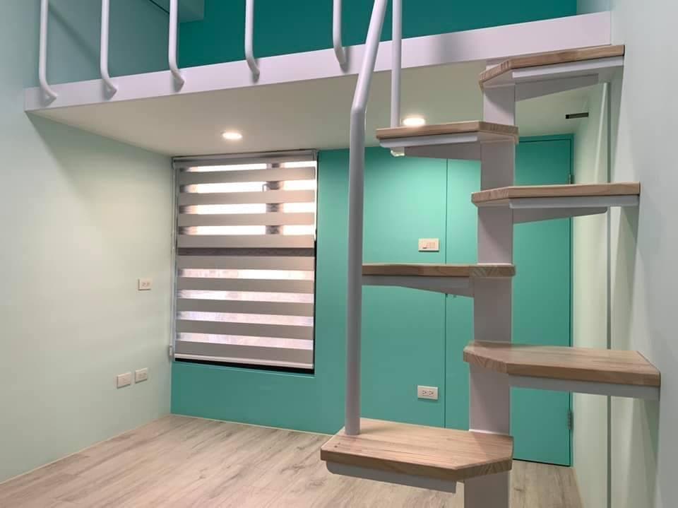 1) 照片顯示一個白色樓梯,樓梯上有木質樓梯踏板,樓梯旁邊的牆壁是淺藍色的,牆壁上有一扇窗戶,窗戶上裝著百葉窗