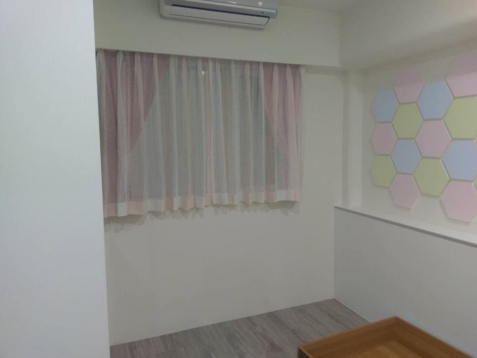 1) 照片顯示一個房間的內部,牆壁是白色,有一扇窗戶,窗戶上有窗簾,牆壁上也有裝飾