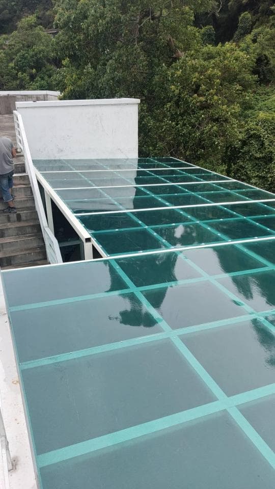 這張照片是一個玻璃屋頂,它由許多透明的玻璃板組成,這些玻璃板被白色金屬框架圍住,看起來很堅固,而且可以讓光線穿透,讓室內更明亮。