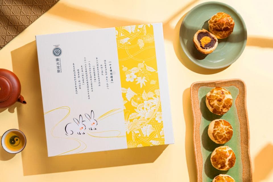 這張「月餅禮盒」的照片是一個精緻的禮盒,上面印有兔子圖案,旁邊擺放著幾個月餅,散發著濃濃的傳統節日氣息。