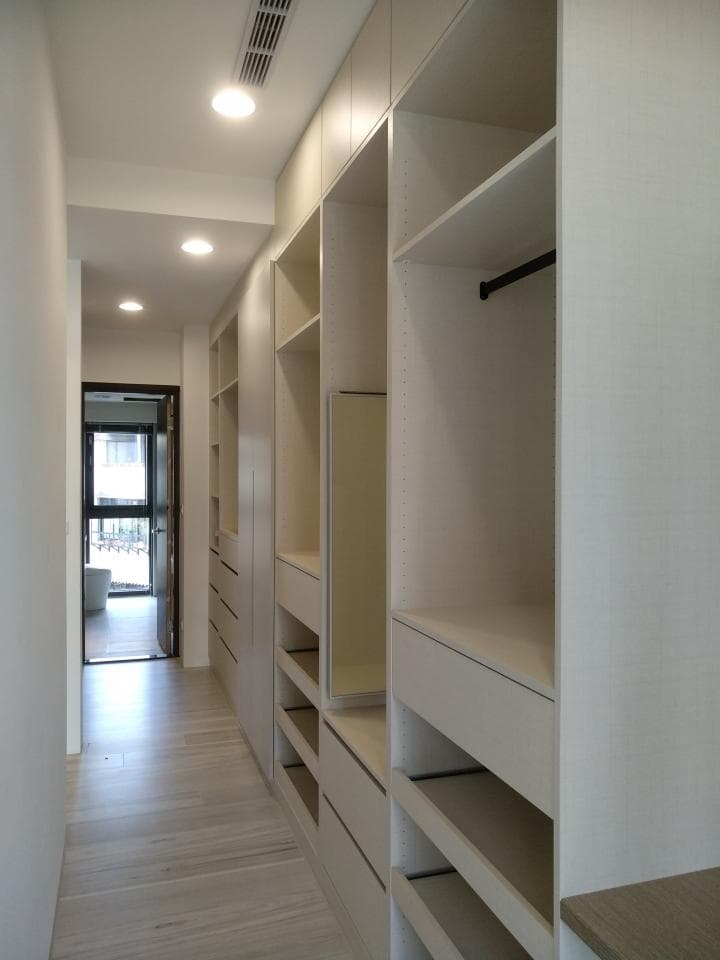 這張照片是一間現代化的衣帽間,牆上裝滿了白色櫃子,看起來很整潔。