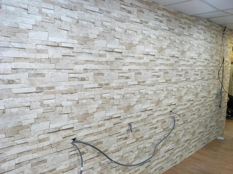 1) 這張照片顯示了一堵由灰色和白色石頭製成的石牆,石頭排列成類似磚塊的樣式,在牆的底部有一些電線和電線