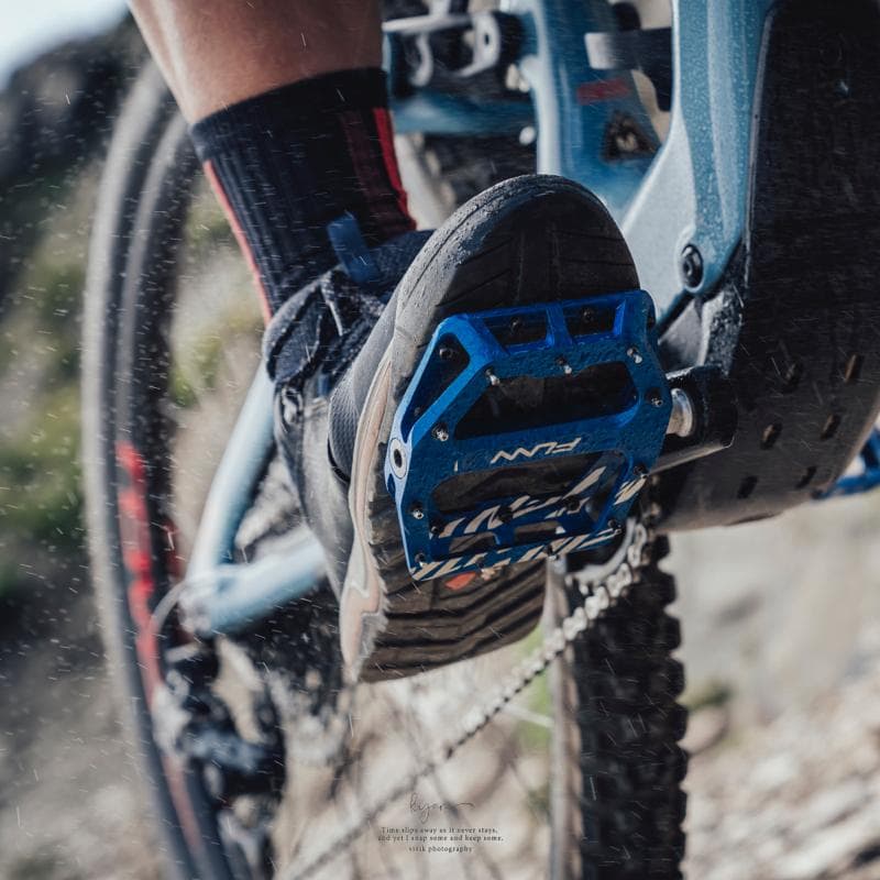 這張「腳踏車」的照片是一個騎車者的腳踩在藍色的腳踏板上,腳踏板上有「FLAN」的字樣。