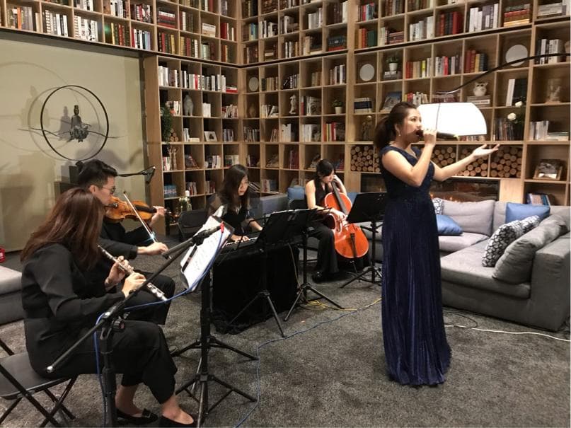 這張「室內演奏」的照片是,一位女歌手在舞臺上唱歌,旁邊有三位樂手伴奏,他們在一個裝滿書籍的房間裡演奏。