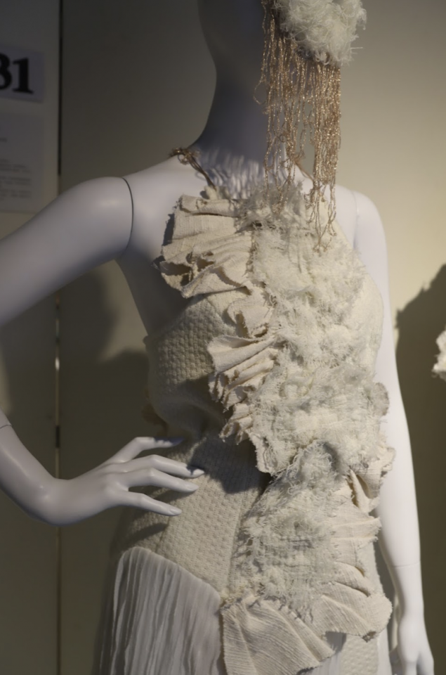 這張照片是一件由白色布料製成的服裝,它以層層疊疊的設計,呈現出不規則的層次感。服裝上覆蓋著蓬鬆的白色裝飾,讓整體看起來更加立體和有趣。