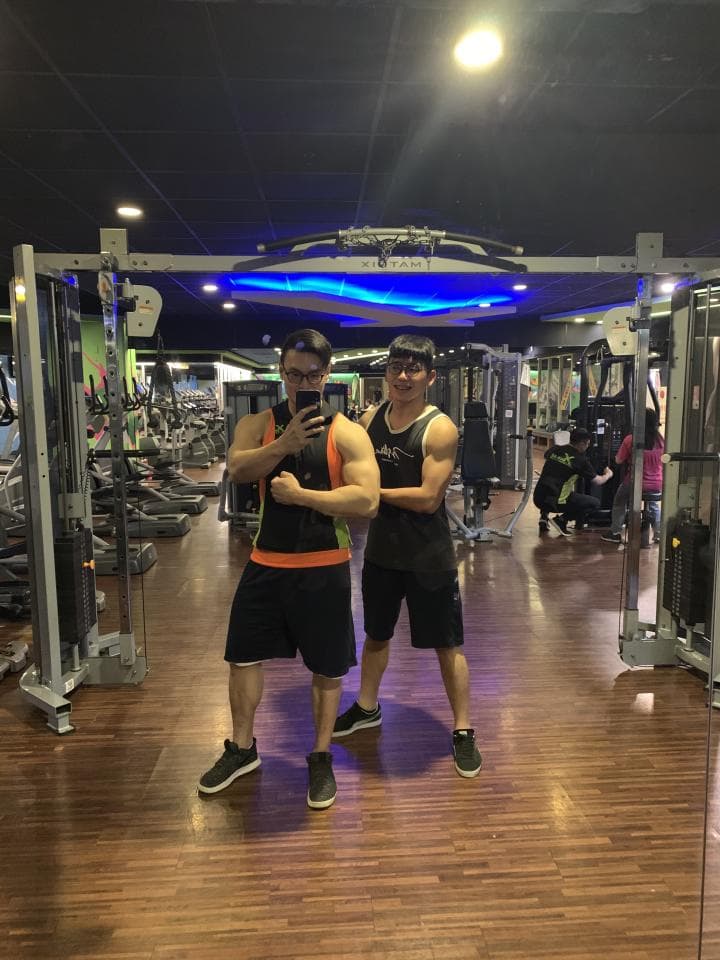 這張照片是兩個男性在健身房裡運動的照片,他們都穿著運動服,其中一個戴著眼鏡,另一個戴著帽子。他們看起來很健康,正在鍛鍊身體。