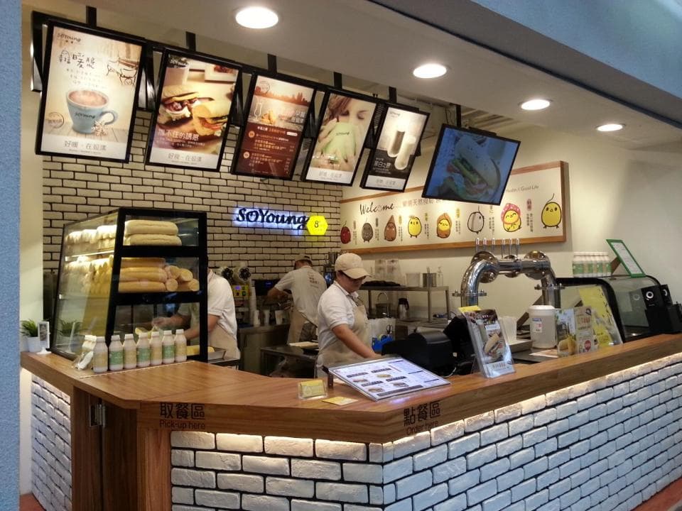 這張照片是 一家餐廳的櫃臺,上面擺著各種不同的食物和飲料。櫃臺後面有一排磚牆,牆上裝飾著一些可愛的圖案。