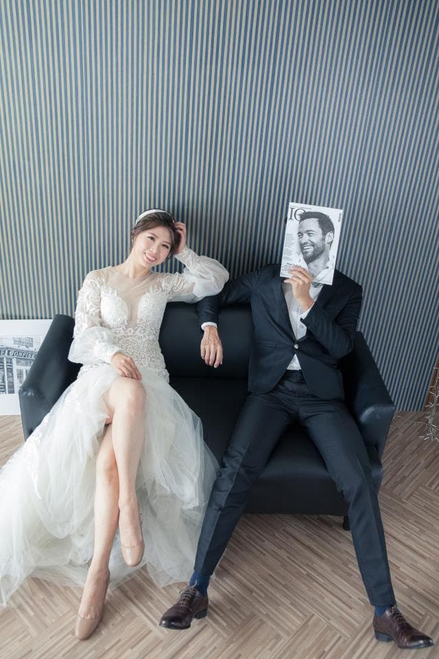 這張婚紗照是一對新人坐在沙發上,新娘穿著白色婚紗,新郎穿著西裝,他們看起來很幸福。