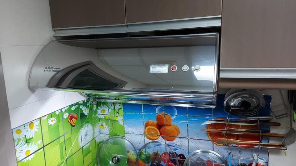 1) 照片顯示一個裝在廚房水槽上方的抽油煙機,它是一個現代化的不銹鋼抽油煙機,帶有彎曲的玻璃面板