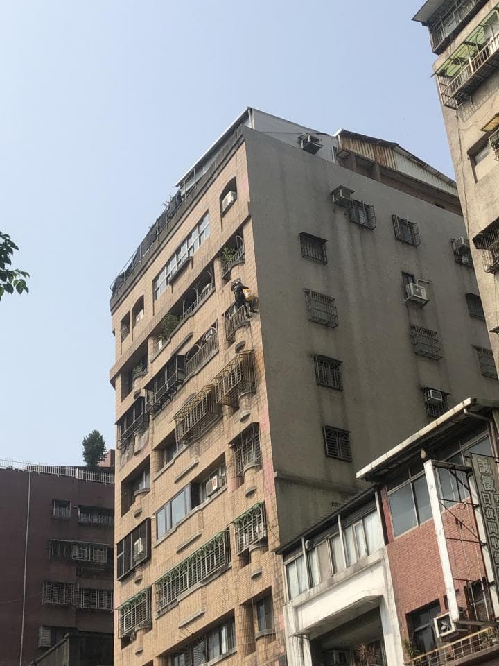 1) 照片描述: 這張照片顯示了一棟多層樓建築物的外觀,建築物的牆壁是米色的,並帶有許多陽台和窗戶