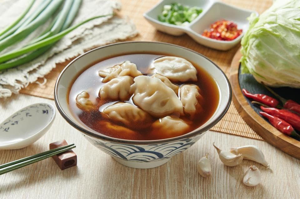 這張「湯麵」的照片是一碗裝滿了湯和餃子,裡面有幾片青菜和辣椒。