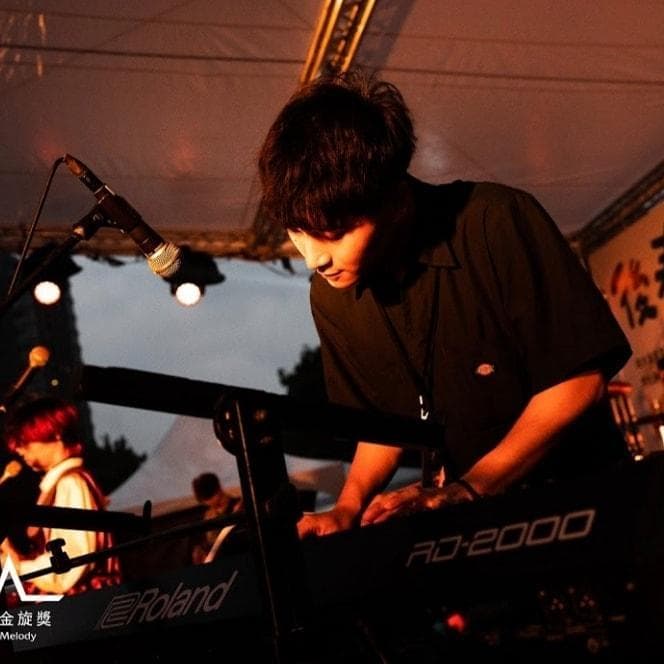 這張照片是一個年輕人正在彈奏 Roland JD-2000 鍵盤。他專注的表情和手在鍵盤上的動作顯示出他對音樂的熱愛。