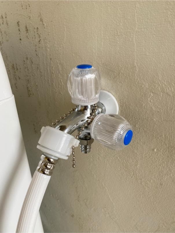 1) 照片顯示一個白色牆壁上的水龍頭,水龍頭上有兩個透明的旋鈕,旋鈕上有藍色的裝飾