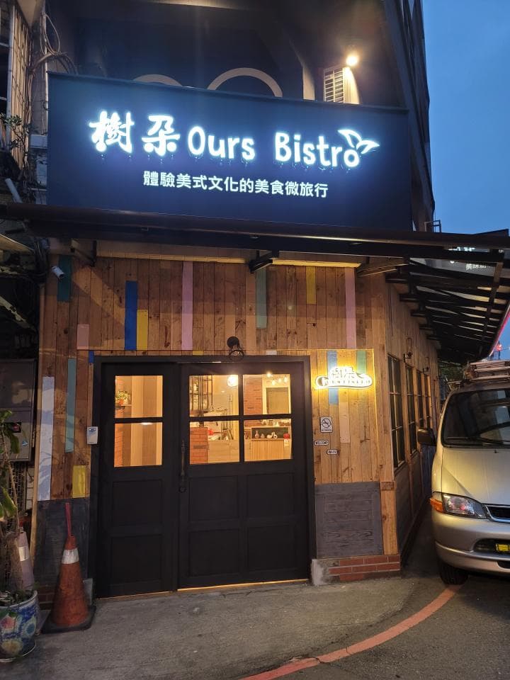 這張「餐廳」的照片是一家名叫「Ours Bistro」的餐廳,招牌上寫著「融合美式文化的美食餐飲店」。餐廳外觀是木板裝飾,有一扇黑色的雙開門。