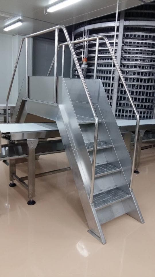 這張照片是一個金屬樓梯,它有六個台階,並配有扶手。樓梯表面光滑,看起來很堅固。