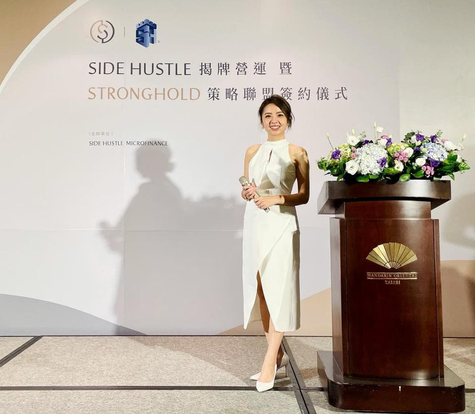 這張「一位女性站在講臺上,穿著白色洋裝,拿著麥克風」的照片是。