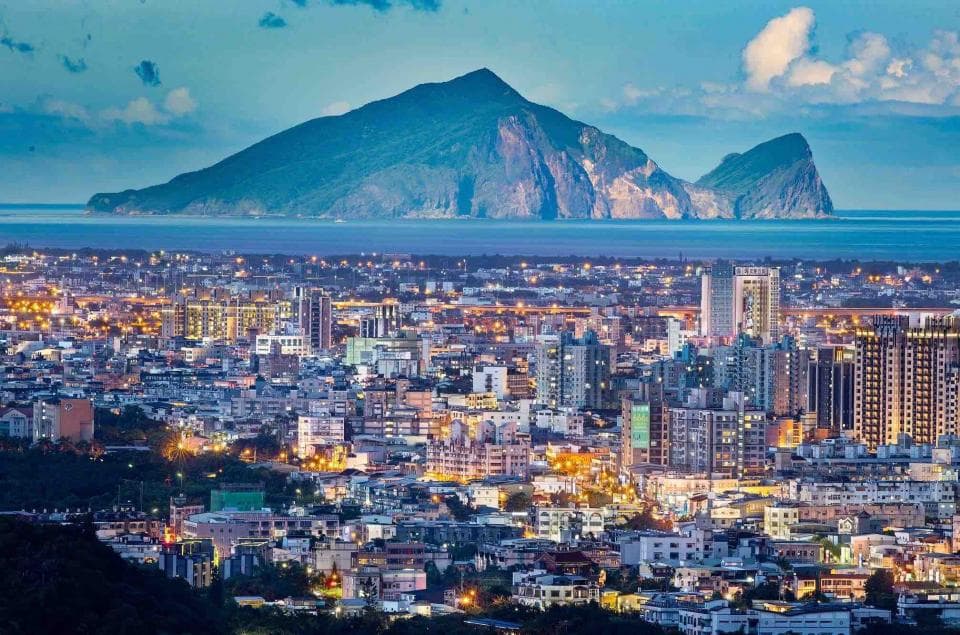 這張「城市風景」的照片是一座山腳下的城市,背景是山和海,城市裡的建築物燈光閃爍,看起來很繁華。