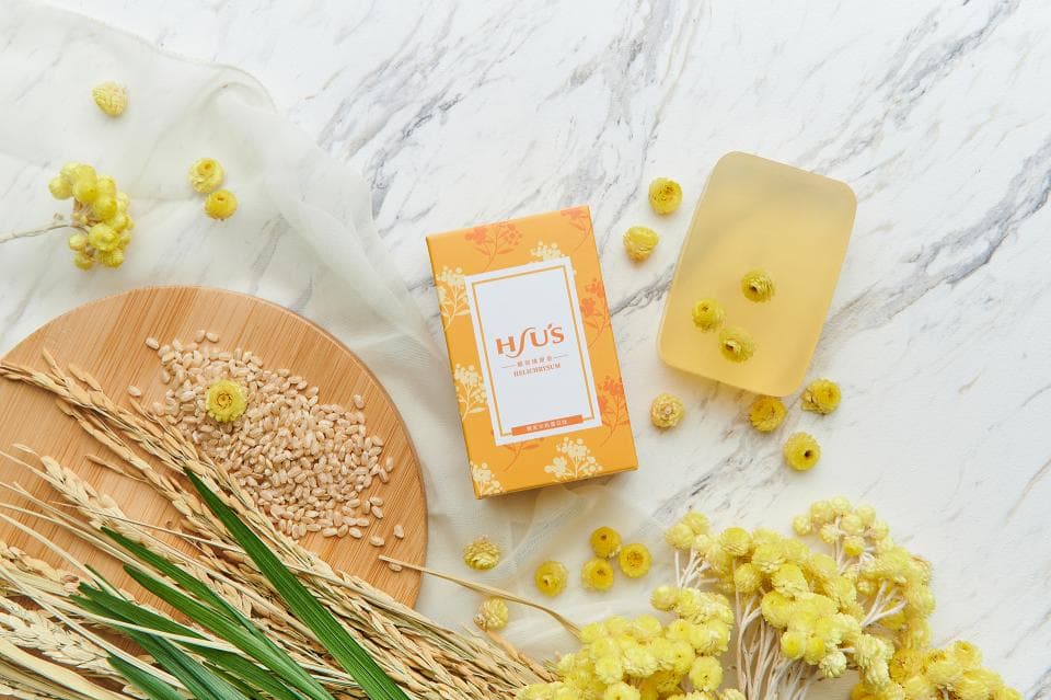 這張照片是一塊黃色的肥皂,看起來很像蜂蜜。肥皂旁邊放著一小束花,看起來像是乾燥的花朵。