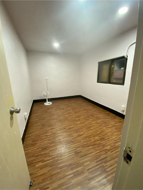 1) 照片顯示一個空房間,房間裡鋪著木地板,牆壁是白色的,天花板上有燈光