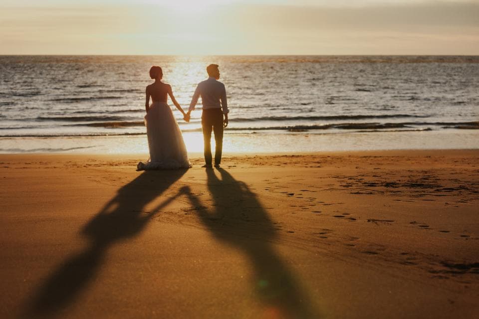 這張「夕陽下,一對新人在沙灘上牽手漫步」的照片是。