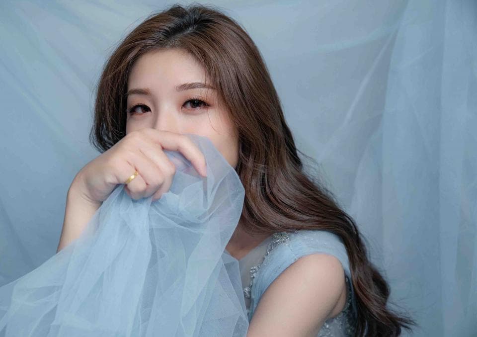 1) 照片中是一位年輕女性,她穿著藍色的紗裙,用手遮住臉,露出半張臉