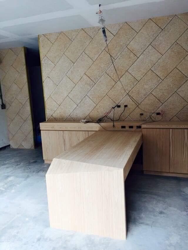 這張照片是一個木質的長桌,桌子的形狀是不規則的,有一部分是直角,另一部分則是斜角,看起來很獨特。