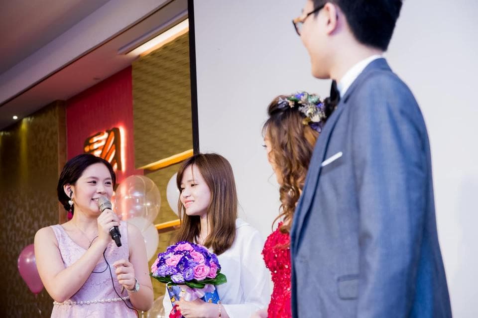 這張「婚禮」的照片是新郎站在新娘旁邊,新娘拿著捧花,一個女伴站在新娘旁邊。