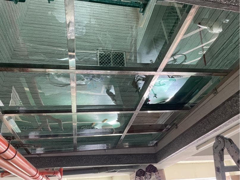 這張「玻璃天花板」的照片是,一個由多個玻璃格組成的天花板,可以看見屋頂和天空。