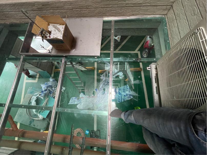 這張「玻璃地板」的照片是一個人站在上面,可以透過地板看到下面的狀況,其中有臺機器和一些雜物。