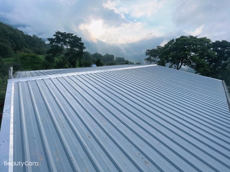 1) 照片顯示一個帶有灰白色金屬屋頂的建築物,屋頂上有一排排的波紋板