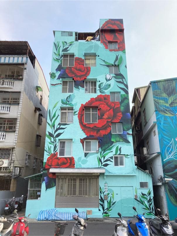 這張照片是一棟以粉藍色為底色,牆面上繪滿紅玫瑰的建築。牆壁上的玫瑰花栩栩如生,讓整棟建築充滿了浪漫的氣息。