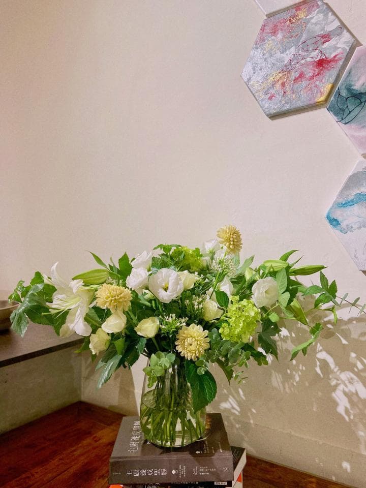 1) 照片中有一個白色花束,放在一個透明的玻璃花瓶中,花瓶放在兩本書上