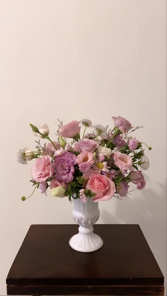 1) 照片中是一束粉紅色和紫色的花,放在一個白色的花瓶中,花瓶放在一個棕色木桌上