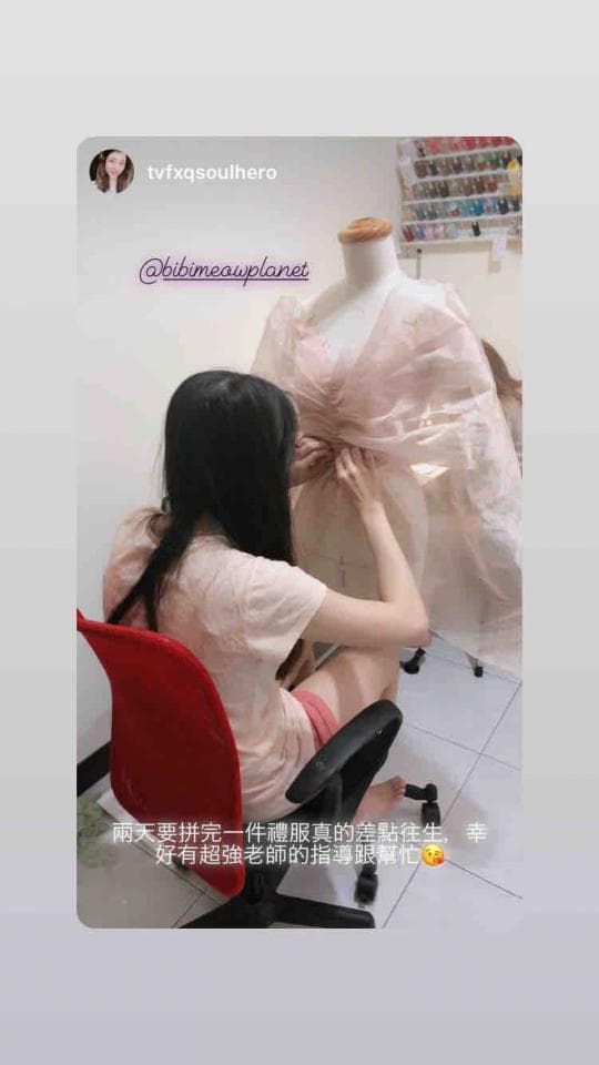 這張照片是一個女孩在縫製一件衣服。她專注地坐在椅子上,用針線仔細地縫著一件粉紅色衣服。