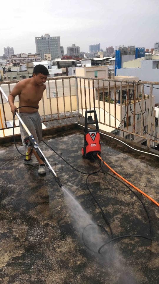 1) 照片顯示一名男子在屋頂上使用高壓清洗機清潔水泥地面