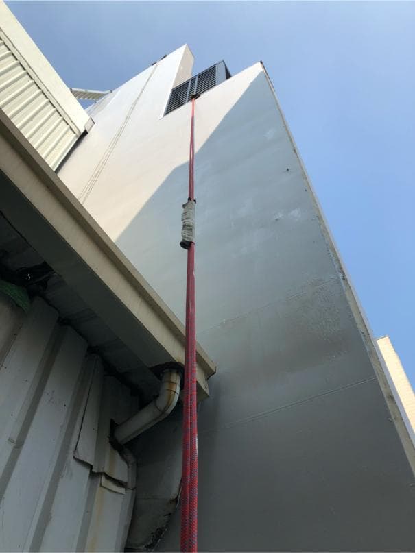 這張照片是一棟建築物的外牆,牆上有一條紅色的繩子,看起來像是用來攀爬或吊掛東西的工具。