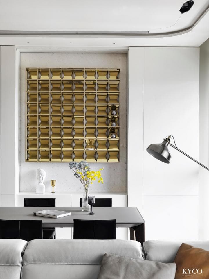 這張「現代家居」的照片是一間客廳,牆壁上有一個金色的酒架,酒架上放著很多酒瓶,客廳裡有一張餐桌,餐桌上放著一束黃色的花,餐桌旁放著一張沙發。