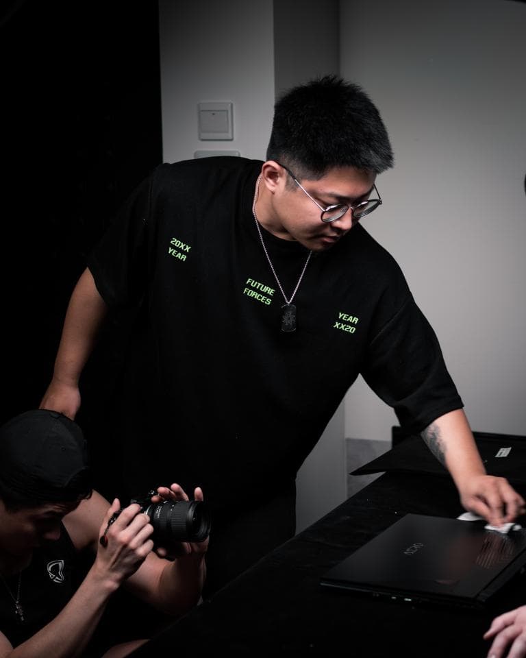 這張「男人正在用筆記型電腦工作」的照片是,他戴著眼鏡,穿著黑色的 T 恤,上面印著綠色的字。