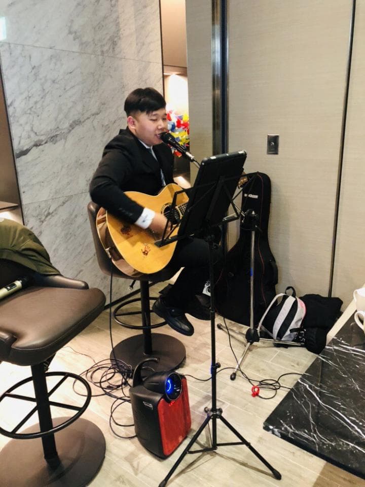 ## 照片資訊
**1) 照片描述** 一位年輕男子在舞台上彈吉他唱歌