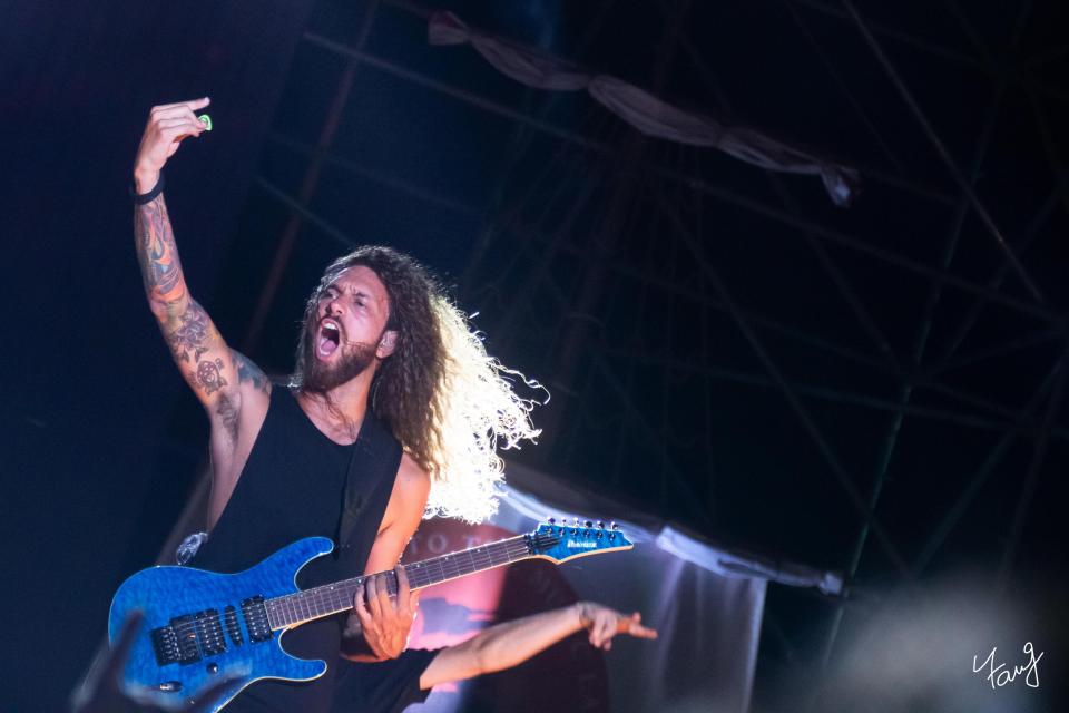 這張「搖滾音樂會」的照片是一個有長頭髮的男性歌手,他正在演奏電吉他,並且唱得很投入。