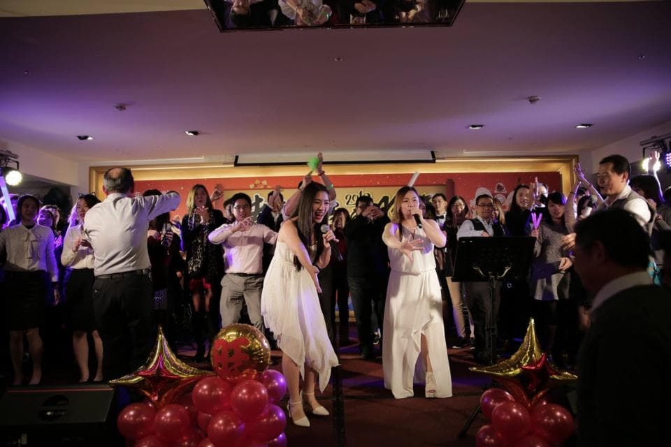 這張「婚禮派對」的照片是一群人在一個宴會廳裡跳舞唱歌慶祝。照片中有一對新人,他們手拿著麥克風唱歌,其他嘉賓們圍繞著他們,開心熱鬧。