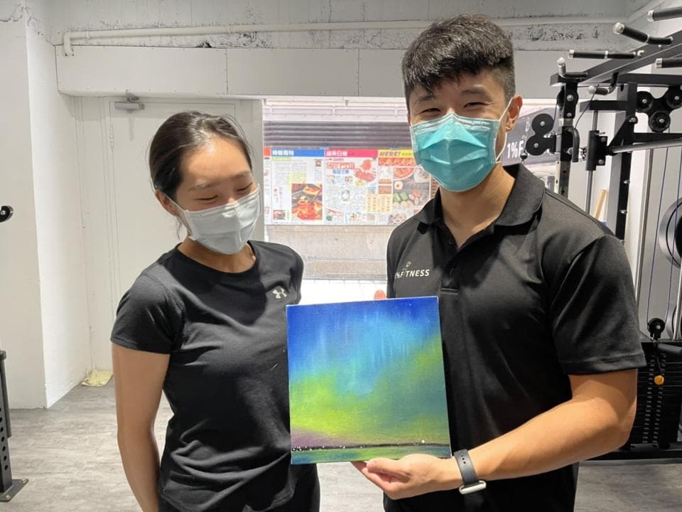 這張照片是兩個朋友,他們拿著一張畫作,上面是美麗的綠光,代表著希望和新開始。