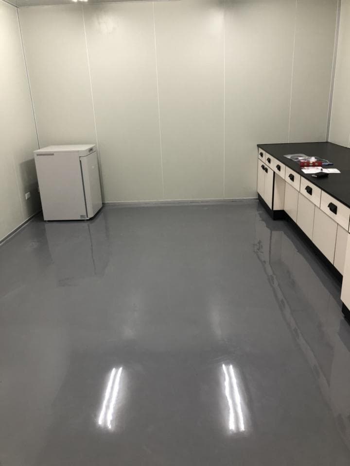 1) 照片顯示一個空房間,房間裡有一個白色冰箱和一個工作台,房間的牆壁是白色的,地板是灰色的