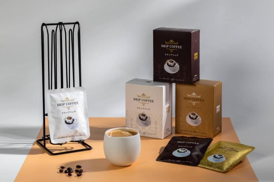 這張「滴濾咖啡」的照片是三盒不同的滴濾咖啡包裝,還有裝著咖啡粉的袋子,以及一杯咖啡。